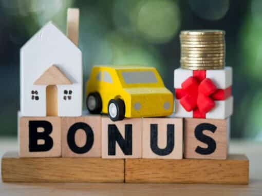 Blocs en bois formant le mot BONUS avec une petite voiture jaune, une maison et une pile de pièces pour illustrer l’avantage en nature véhicule 2025 et son impact financier.
